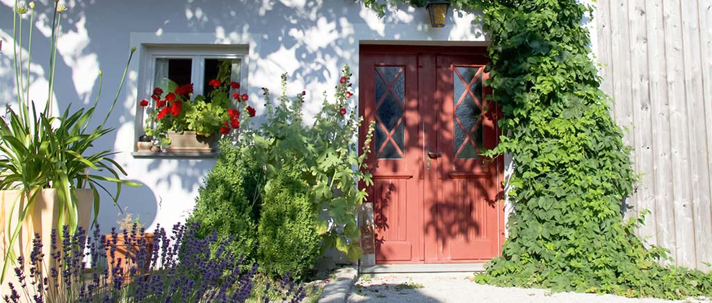 Rote Haustür und Fenster mit Geranien