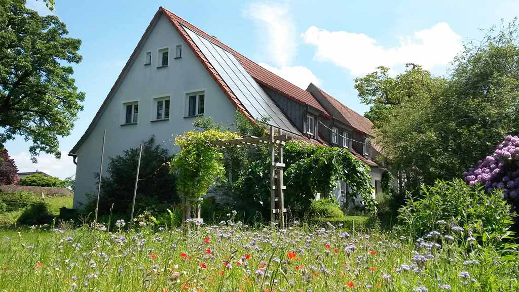 Blau-graues Haus mit Blumenwiese im Sommer